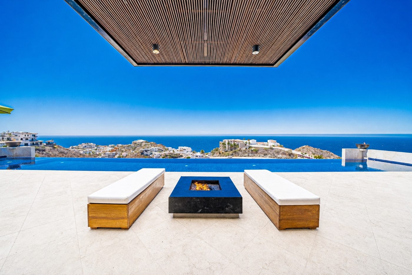 Pergola-covered fire pit lounge with twin benches and ocean view