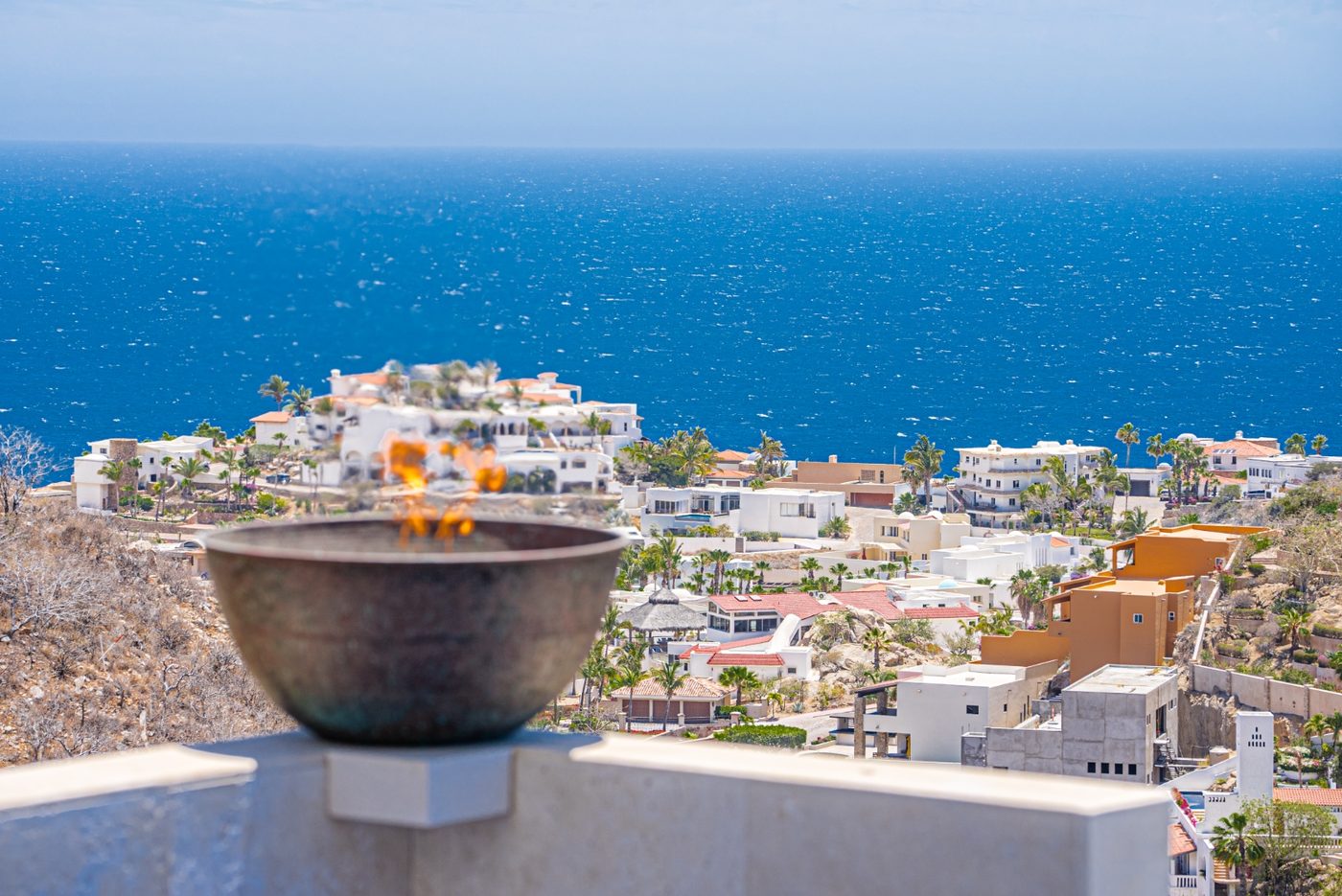 Bronze fire bowl on the pool deck with infinity edge and bay view